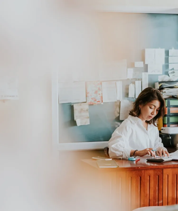Mulher oriental de cabelo castanho e blusa branca trabalhando em escritório