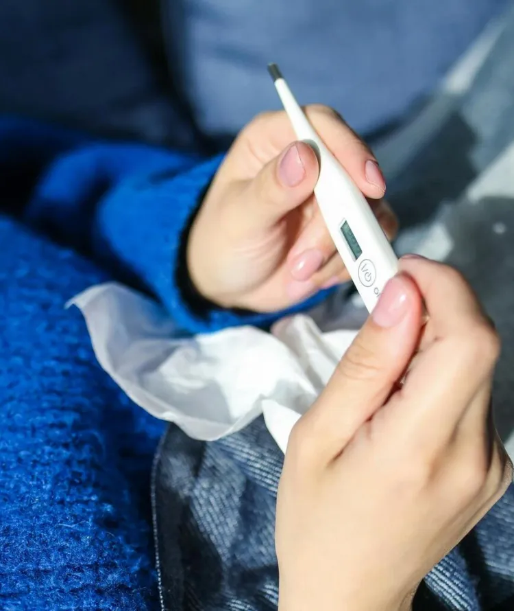 Mulher segurando termômetro com blusa azul 